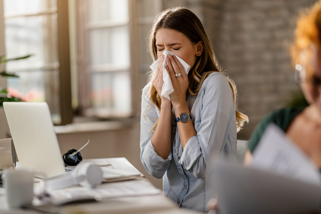 young-sick-businesswoman-sneezing-tissue-while-working-office
