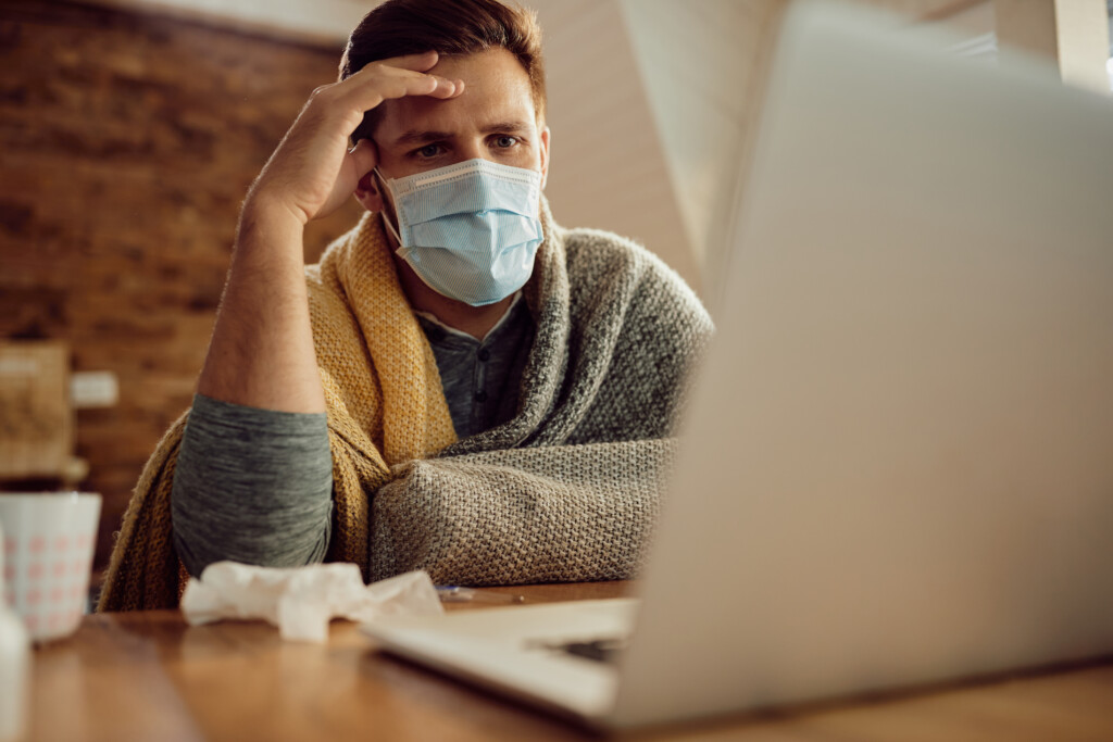 pensive-man-with-face-mask-using-laptop-home