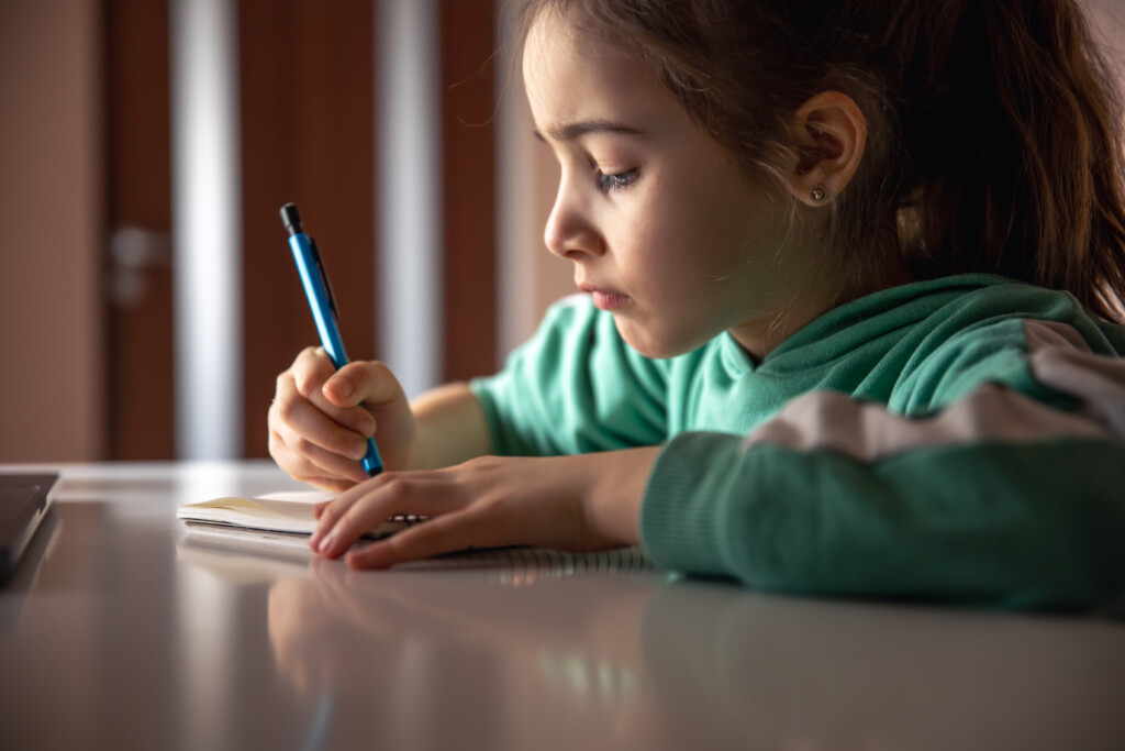 serious-little-girl-writes-with-pen-notebook