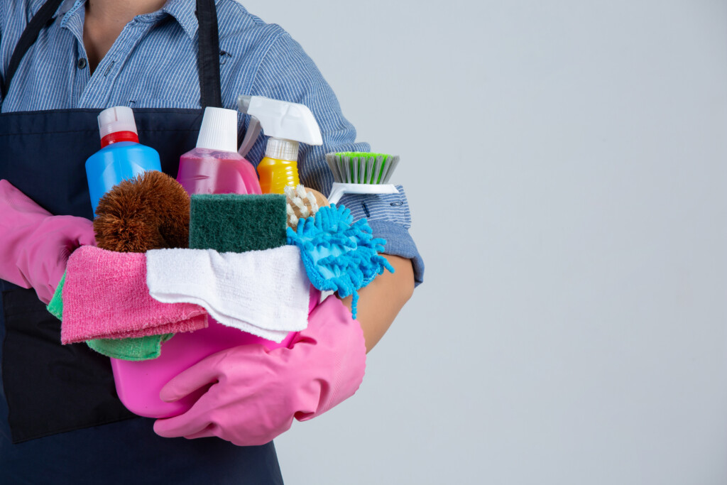 woman-is-holding-cleaning-product-gloves-rags-basin-white-wall